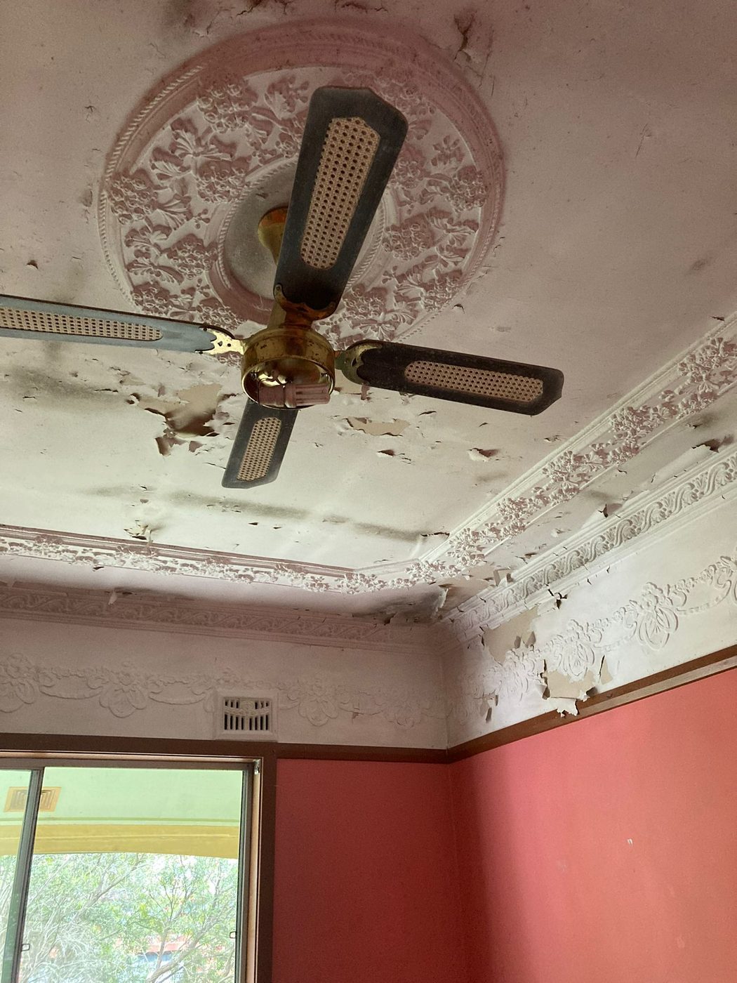 Room with wall linings removed exposing timber framing, floor covered with stored items and tools